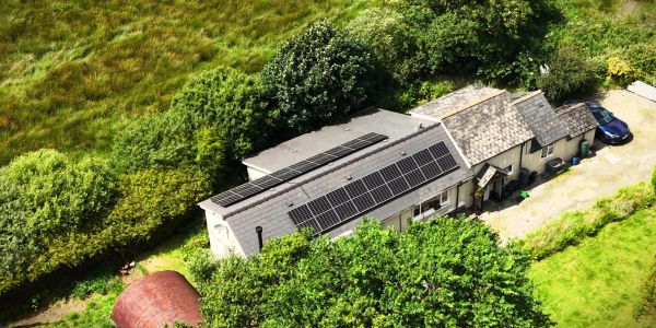 House with solar panels on the roof surrounded by greenery.