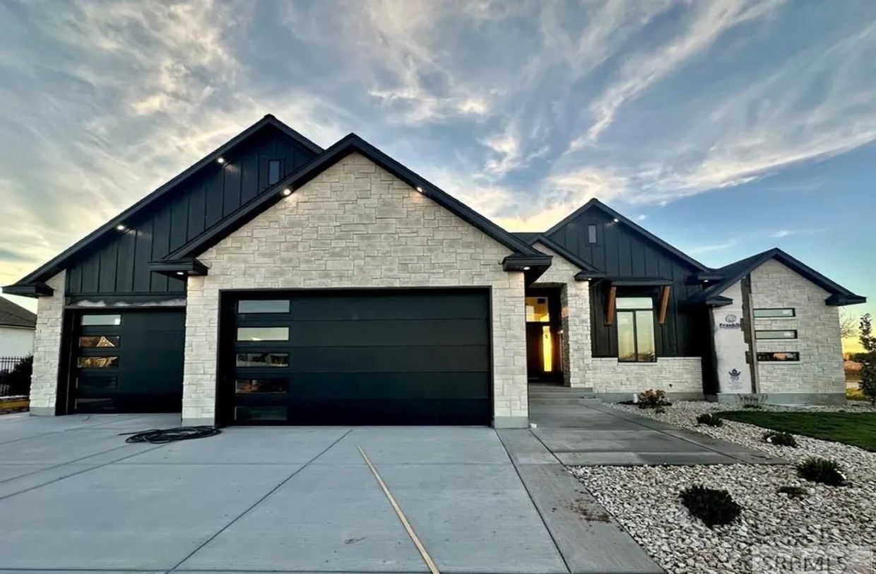 Modern house with stone and dark panel exterior under a dramatic sky.