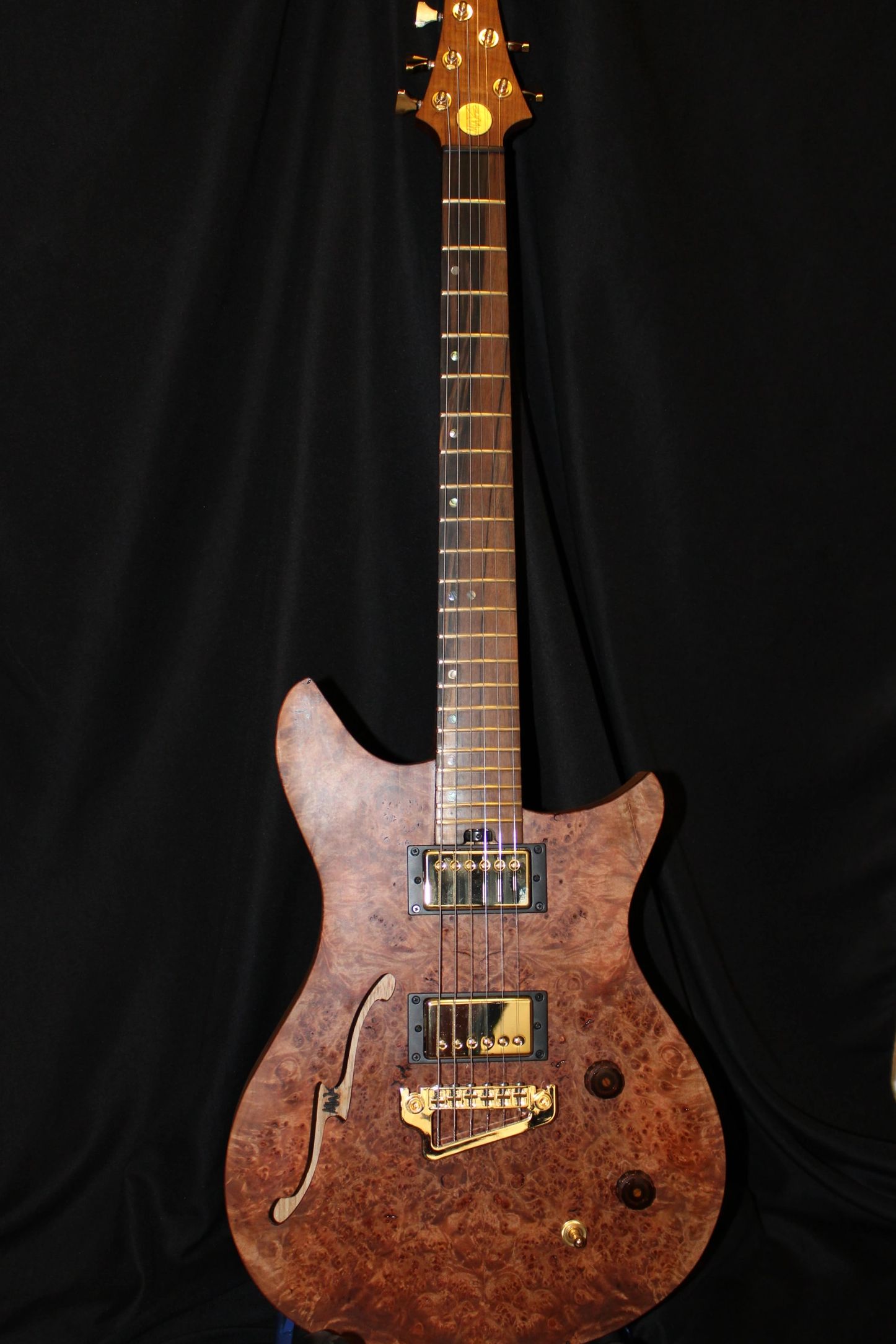 An EP model with maple burl top and swamp ash body. It features a 25" scale with a 12" radius finger