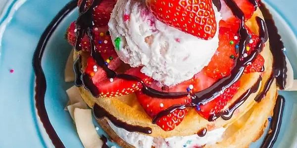 Waffle with strawberries, chocolate, coconut pieces and whipped cream.