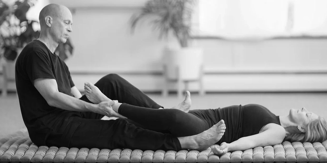 Black and white image of a man stretching a lady leg