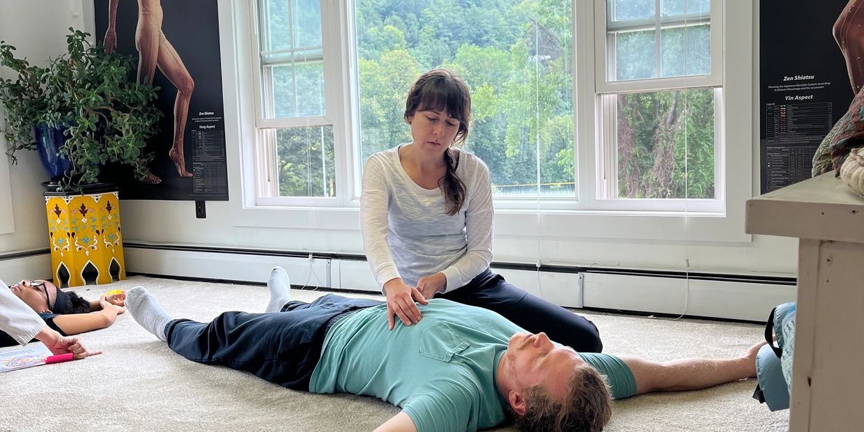 A girl giving massage to a man lying on the floor