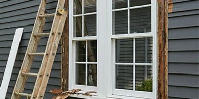 Window installation with ladders against siding.