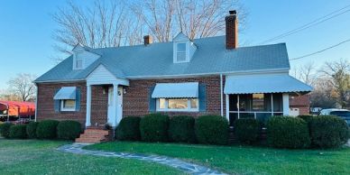 Brick house with blue roof and trimmed bushes.