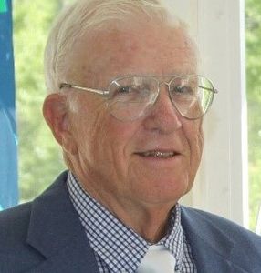 Portrait of an elderly man wearing glasses and a suit.