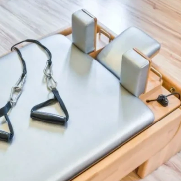 Pilates reformer machine with straps and cushioning.