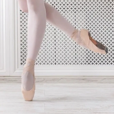 Ballet dancer on pointe in pink tights and shoes.