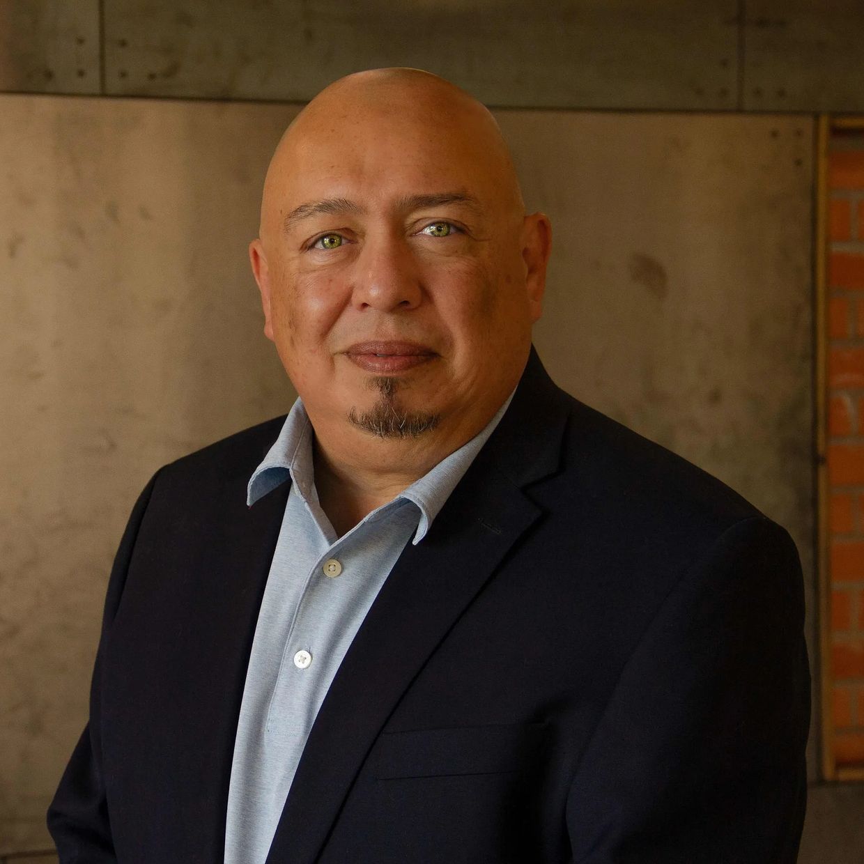Bald man in a suit posing indoors.