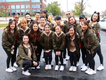 A group of young people in matching jackets posing outdoors.