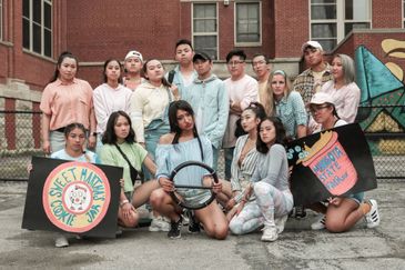 Group of young people posing outdoors with themed signs and props.