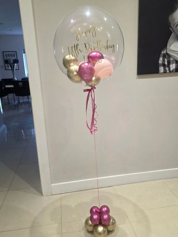 helium bubble balloon with pink ribbon, pink and gold balloons and a pink bow 