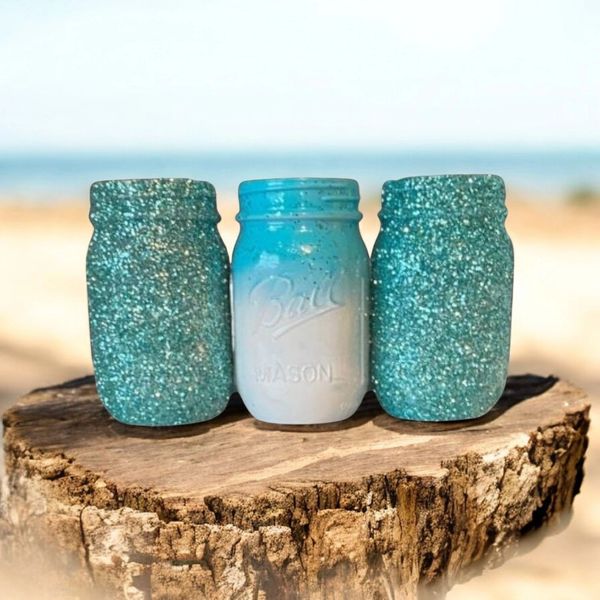 Three mason jars with blue and white gradient on a tree stump.