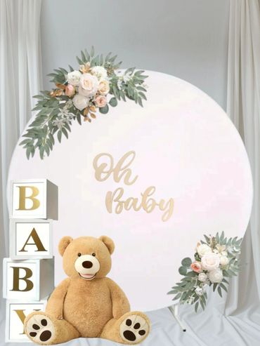 Baby shower setup with teddy bear and floral decorations.