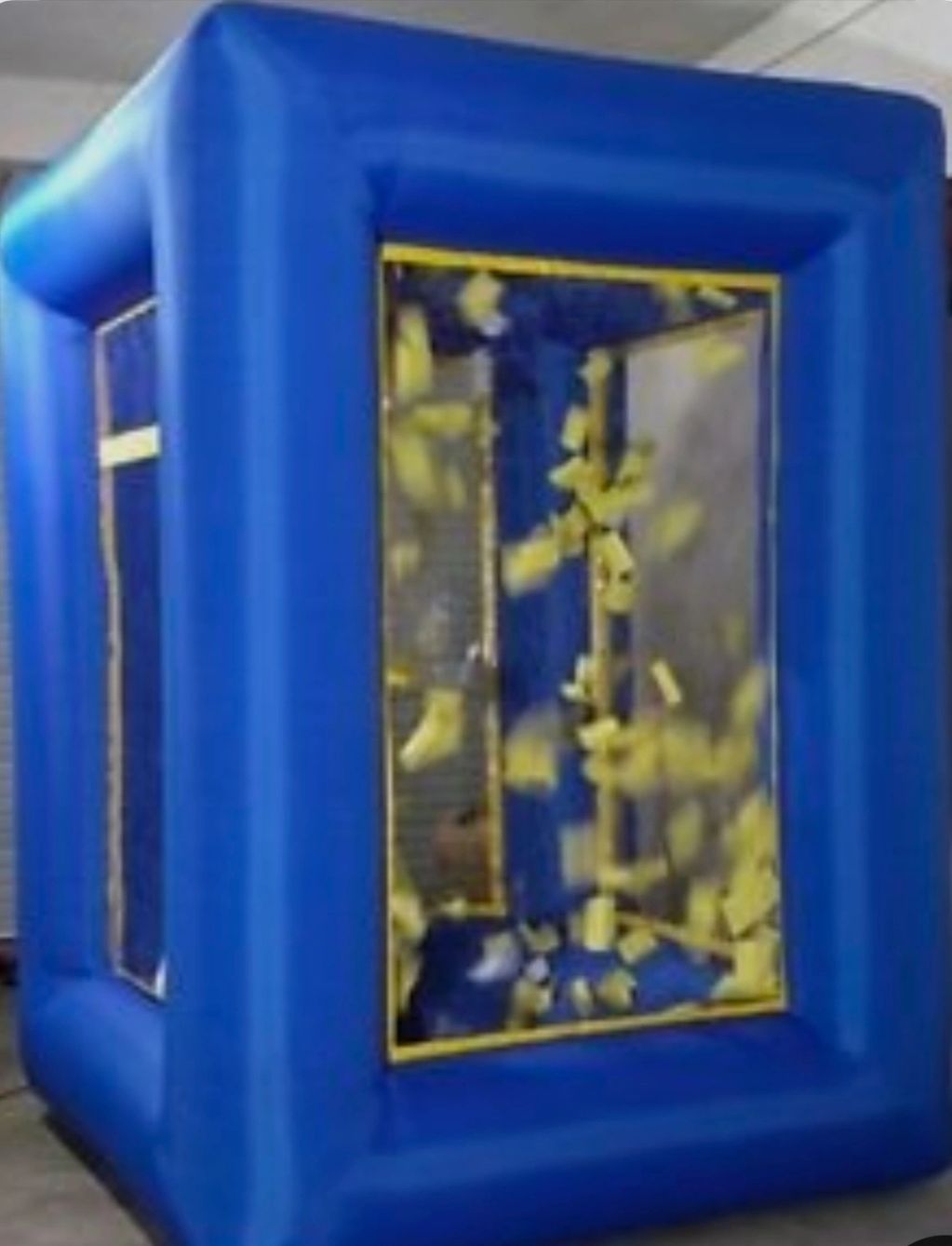 Inflatable blue booth filled with swirling yellow foam pieces inside.