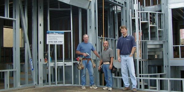 Three men standing inside a building under construction.
