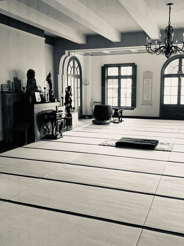 A serene, traditional Japanese tatami room with statues and soft natural light.