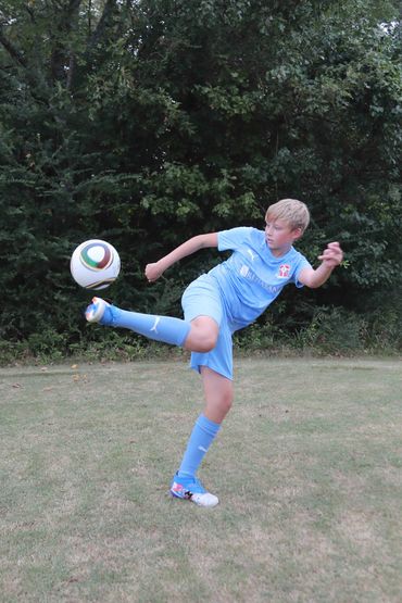 Young boy kicking a soccer ball outdoors.