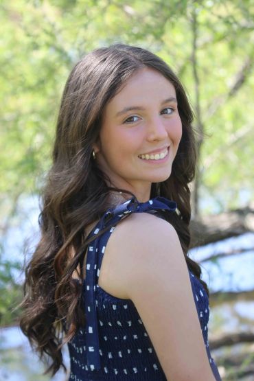Young woman smiling outdoors with long hair.