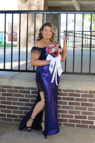 Young woman in a sparkling purple dress holding a bouquet.