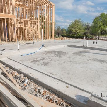 Concrete foundation and wooden frame of a building under construction.