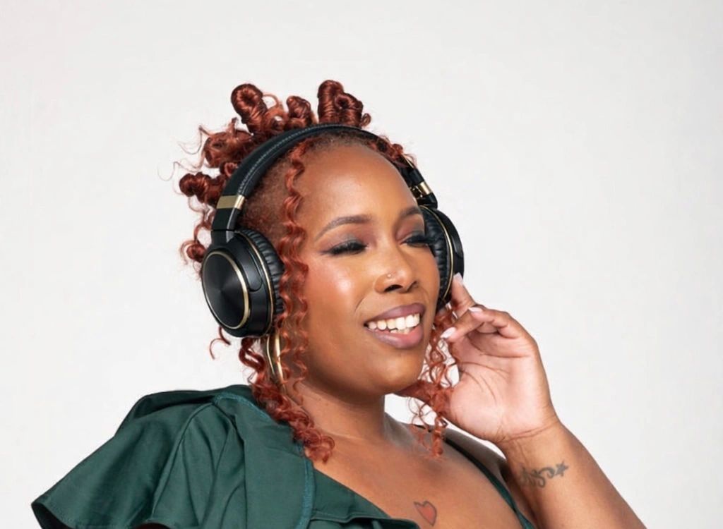 Woman with curly hair enjoying music on black headphones.