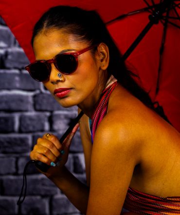 Woman with sunglasses holding a red umbrella.