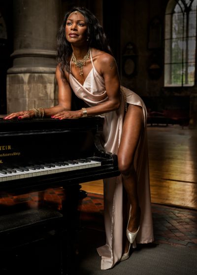Elegant woman in satin dress leaning on a grand piano.