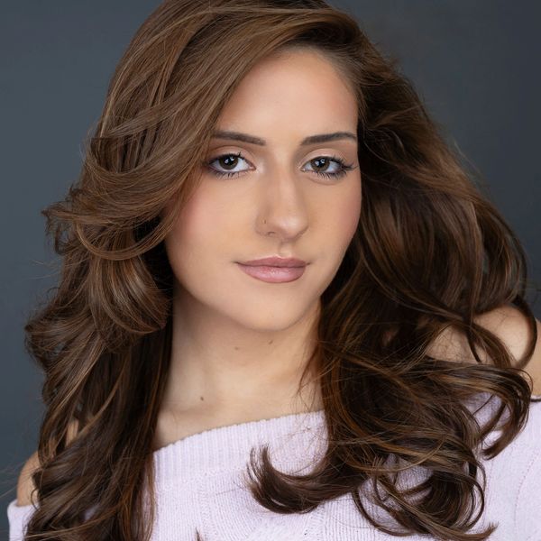 Portrait of a young woman with flowing brown hair and subtle makeup.