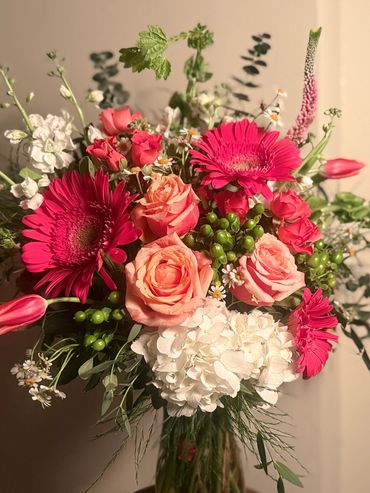 Vibrant bouquet with pink gerberas, peach roses, and white hydrangeas.