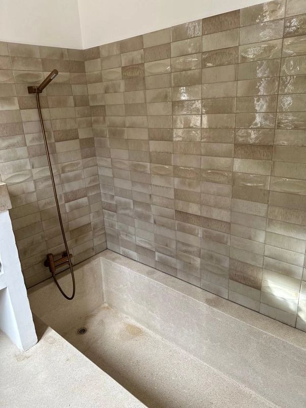 Douche avec un bac incrusté dans le sol en béton tarrazzo et mur en carrelage
