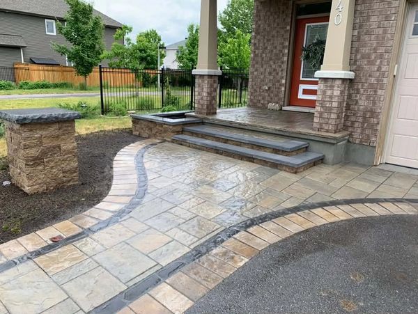 Newly installed wet stone walkway and steps leading to a brick house entrance.