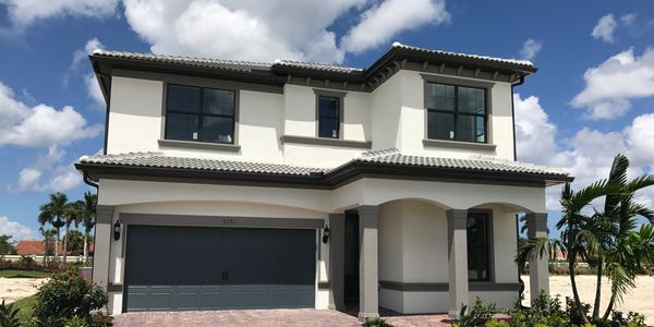Modern two-story house with a gray garage door under a cloudy blue sky.