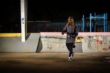A woman walks alone at night in an urban skate park.