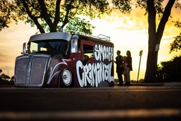A customized truck with graffiti art reading 'Smokey Criminal' at sunset.