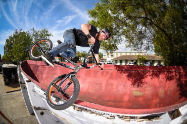 A BMX rider performs a trick on a red ramp outdoors.