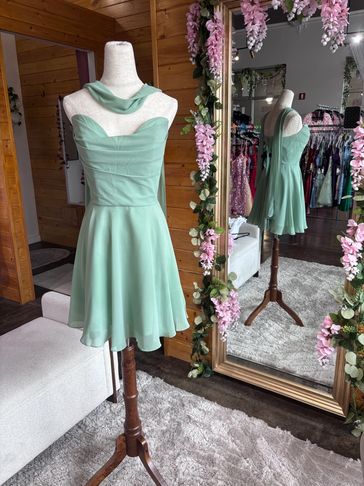 Mint green dress on a mannequin near a floral decorated mirror.
