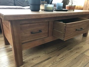 Wooden coffee table with one drawer open.