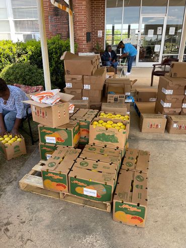 People organizing boxes of lemons outside a building.