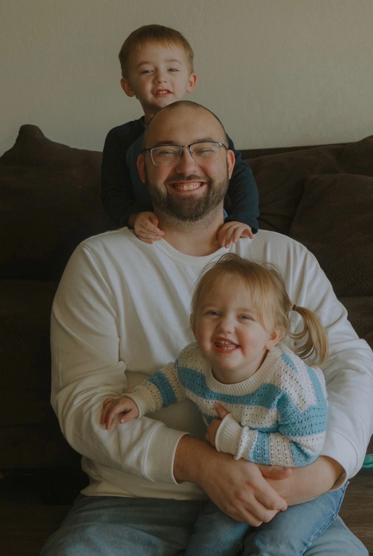 Smiling father with two happy children in a warm, cozy setting.