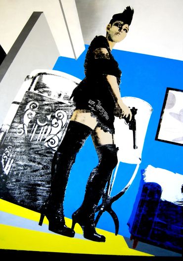 Edgy woman with a mohawk and gun in a bold, graphic room.