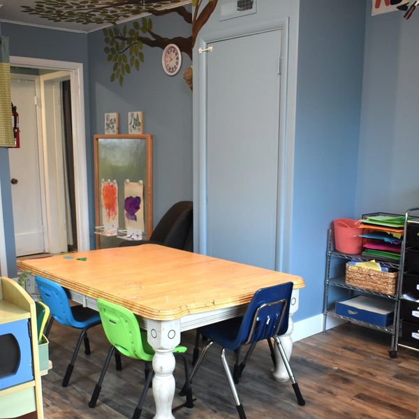 Colorful chairs around a wooden table in a children's classroom.