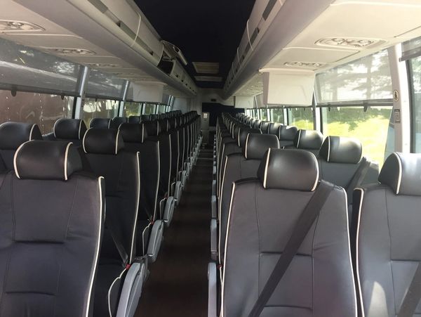 Interior view of an empty modern coach bus with black leather seats.