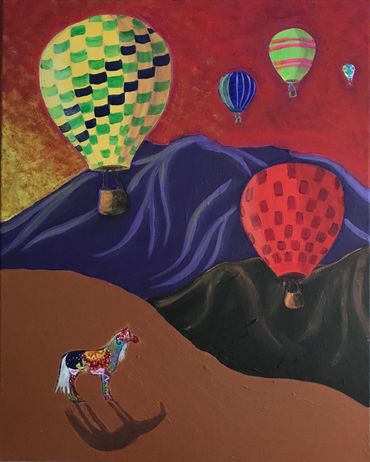 The painted horse watches balloons rising at sunrise. The Sandias are n the background.