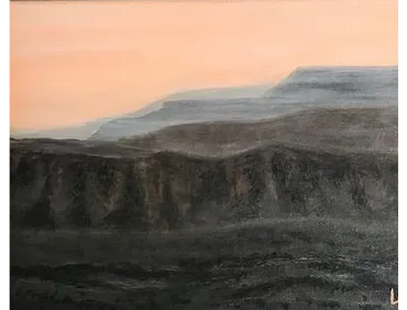 A peach-colored sky renders the mesas almost smoky as the sun disappears from the sky.