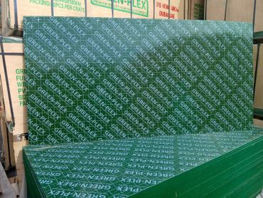 Stacks of green plywood sheets branded 'GREEN-PLEX' in a storage area.