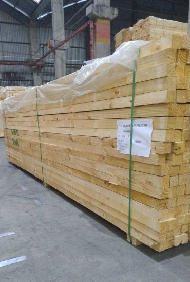 Stacked wooden planks bundled and stored in a warehouse.