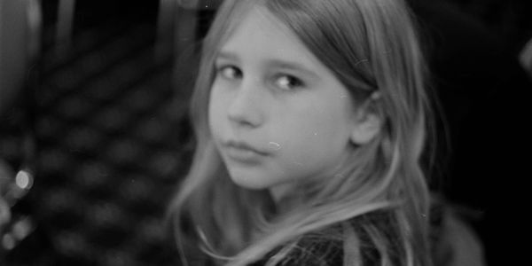 Black and white portrait of a young girl looking back over her shoulder.