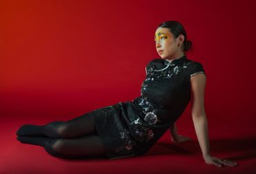 Woman in a black floral dress posing against a red background.