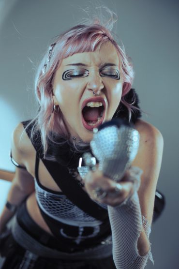 A punk woman passionately singing into a microphone.