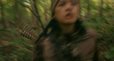 Blurred image of a person in a forest with a quiver of arrows.
